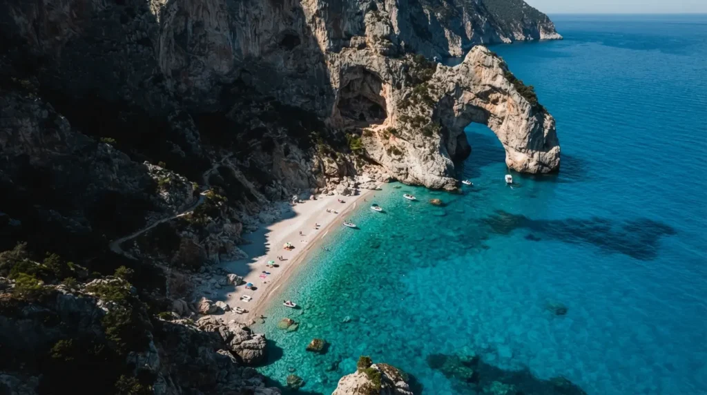 Cala Goloritzé beach on Sardinia's Golfo di Orosei coast viewed from above, with a natural limestone arch rising from the turquoise water and vertical cliffs on all sides 
