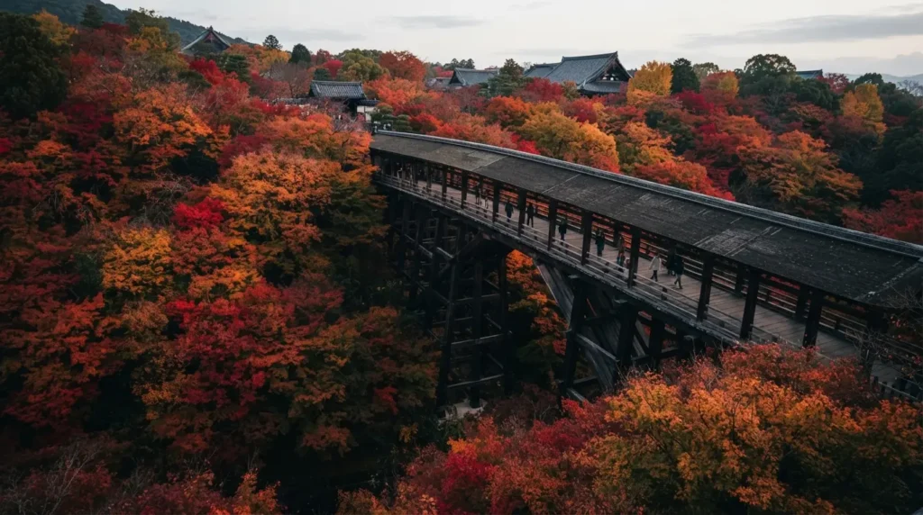 The Tsutenkyo bridge at Tofuku-ji temple in Kyoto crossing a valley of vivid red and orange maple trees in peak autumn colour, visitors on the bridge small against the surrounding foliage